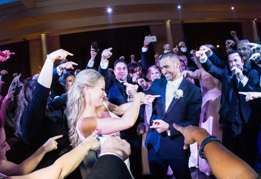 A bride and groom are dancing in front of a crowd of people at their wedding reception.
