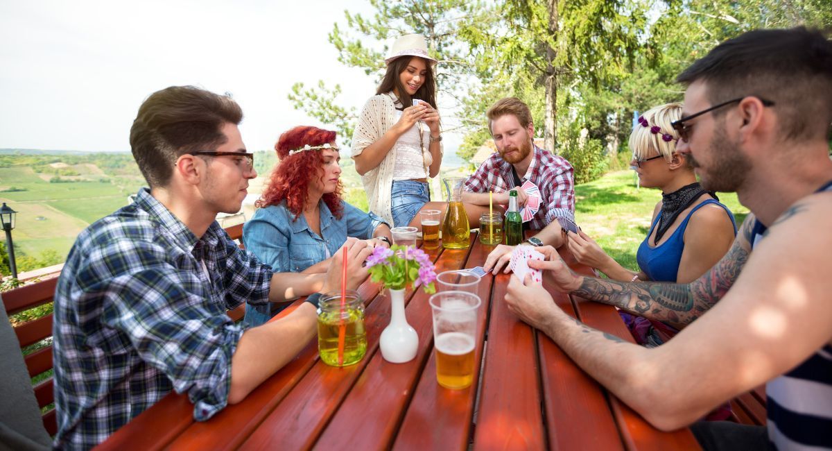 A group of young people are sitting at a table drinking beer.