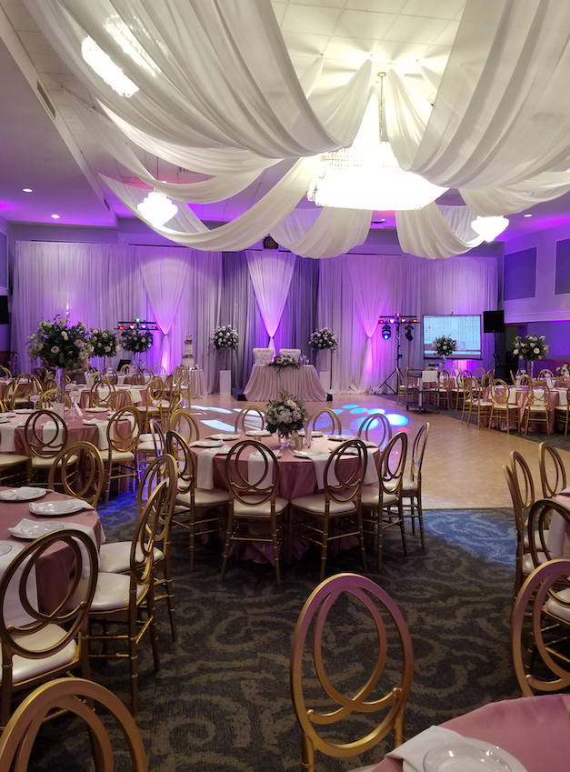 A large room with tables and chairs set up for a wedding reception.