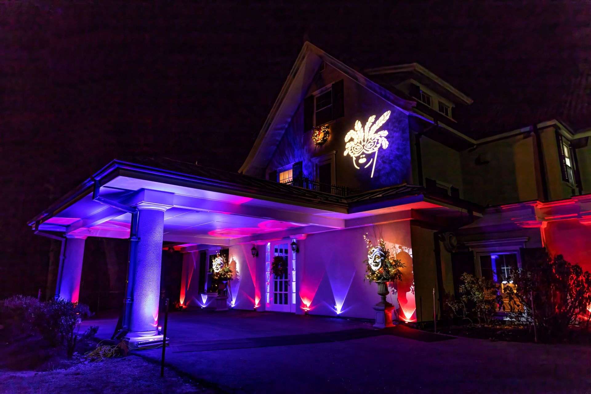A large house is lit up with purple and red lights at night.