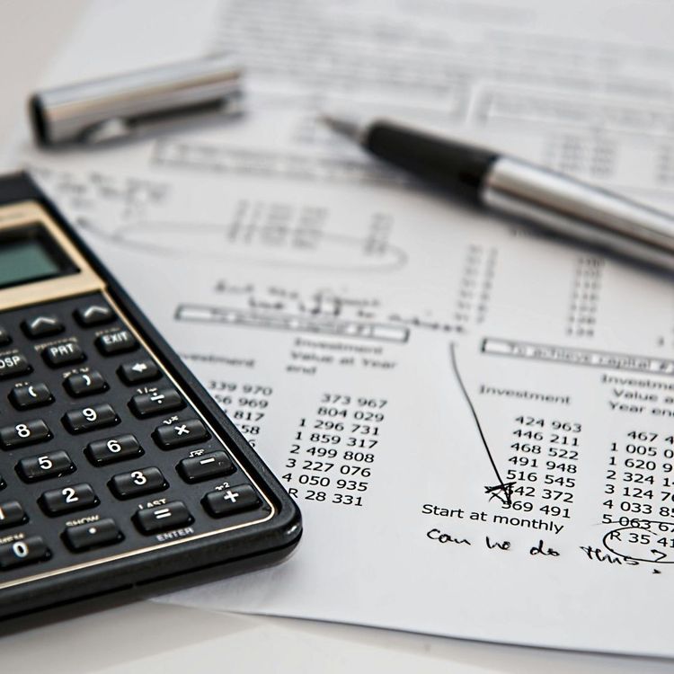 Table top with a calculator, data sheet, and uncapped pen.