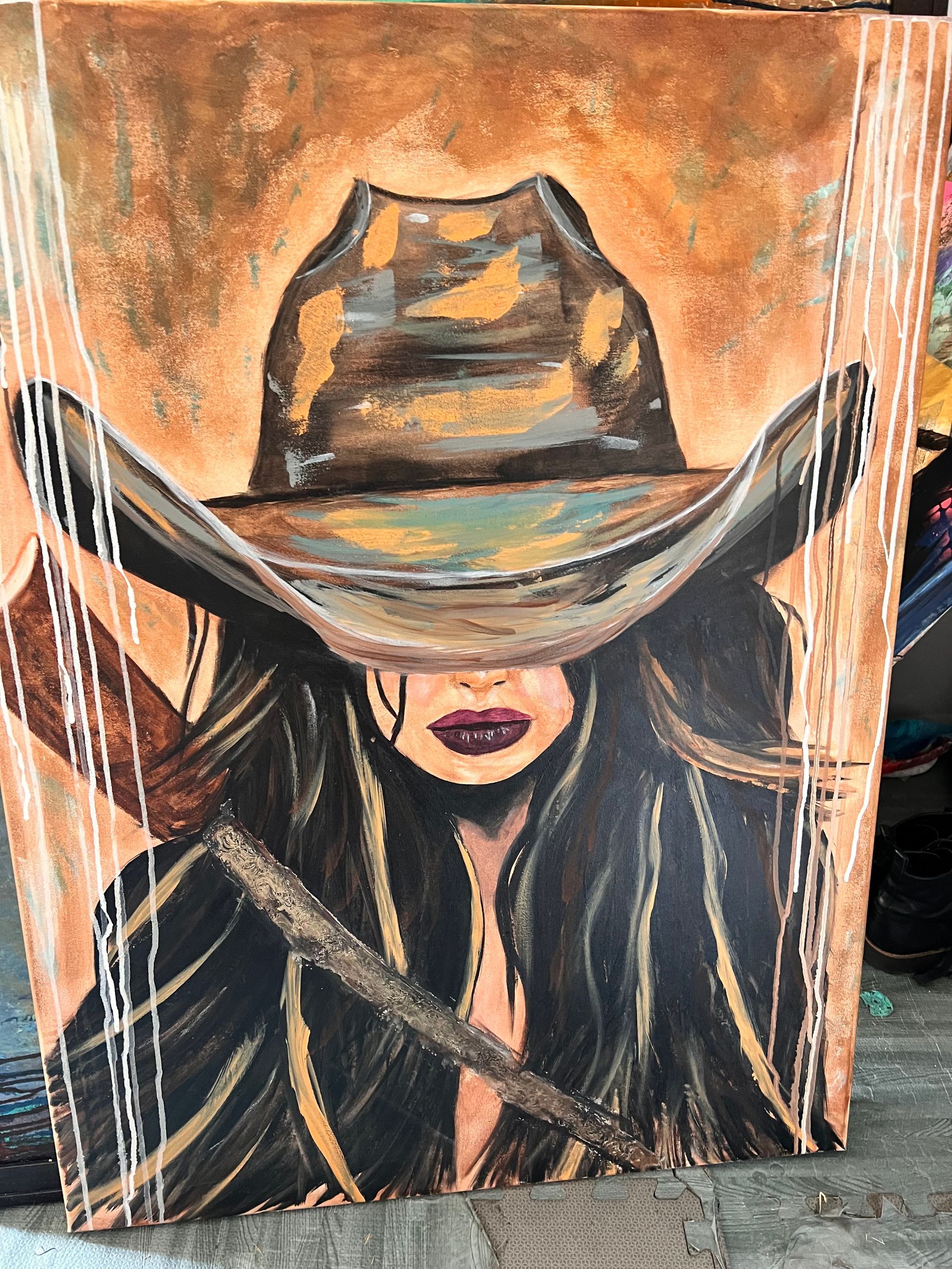Cowboy hat painting with long dark hair, brown and orange hues, with white vertical lines.