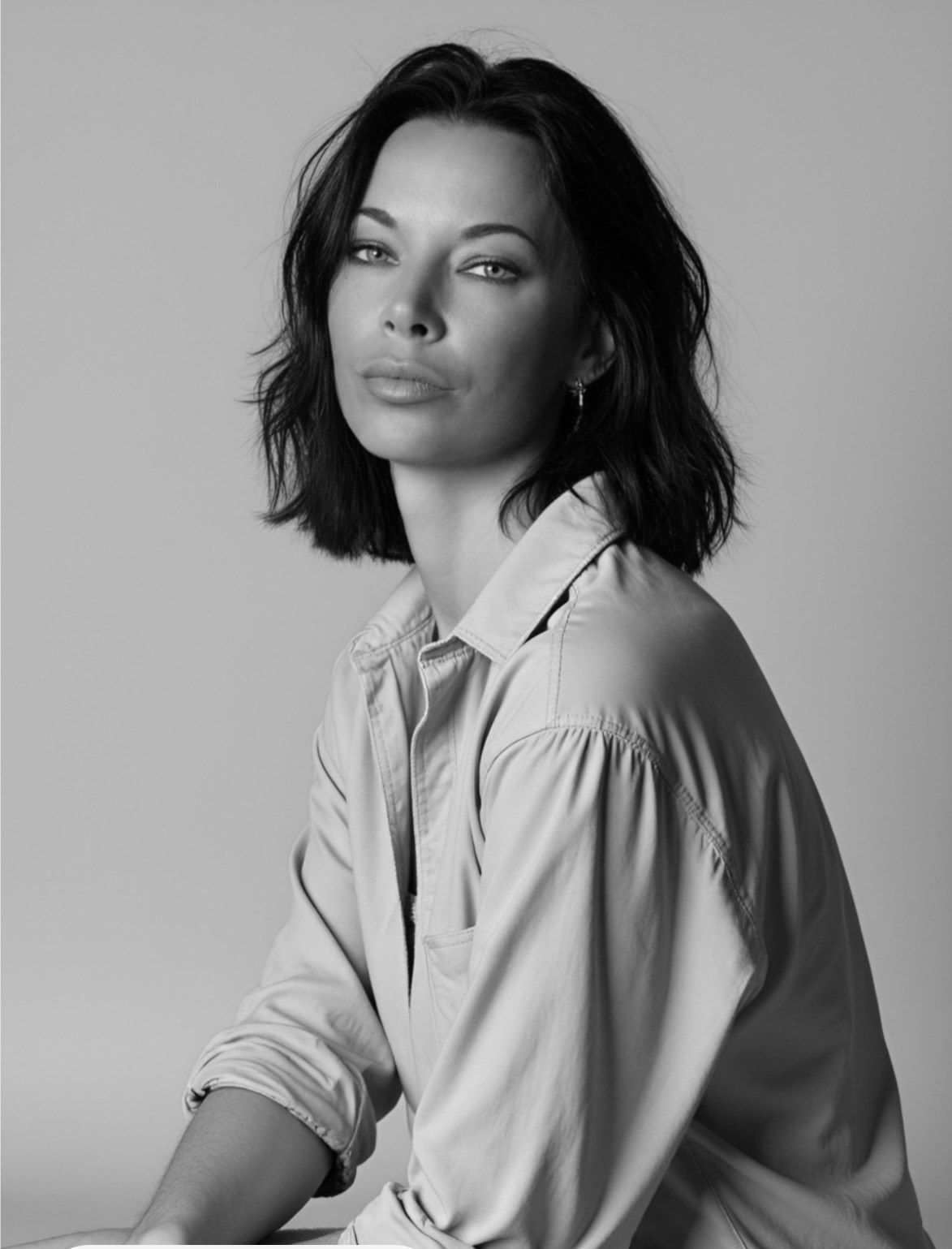 Woman in a light-colored button-down shirt looks at the viewer. Black and white portrait.