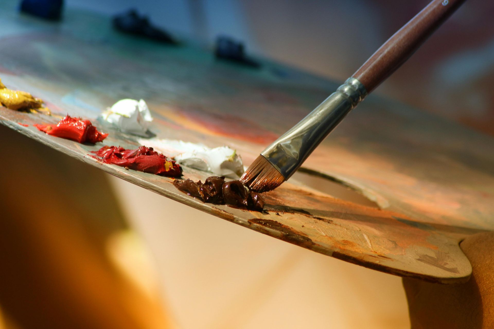 Paintbrush on a wooden palette with dabs of various colors of paint.