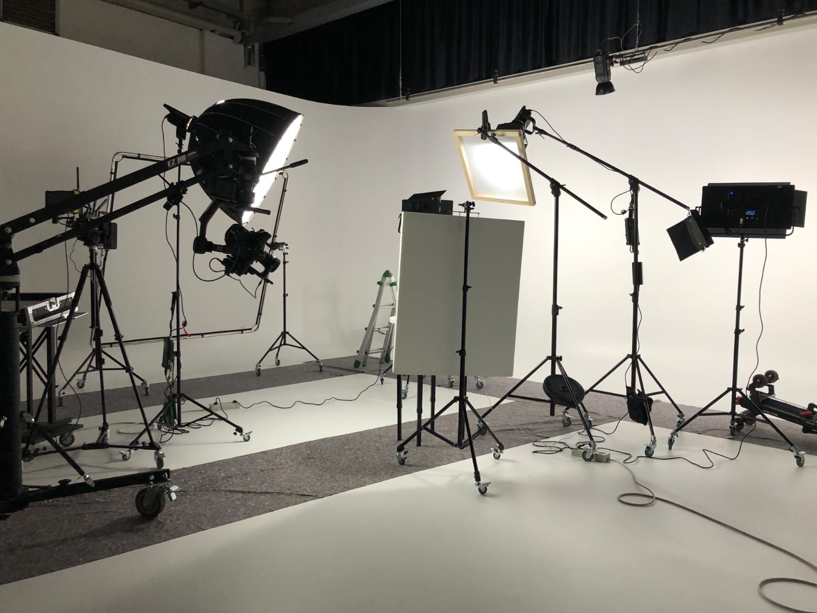 Photo studio with white backdrop and various lighting equipment set up.