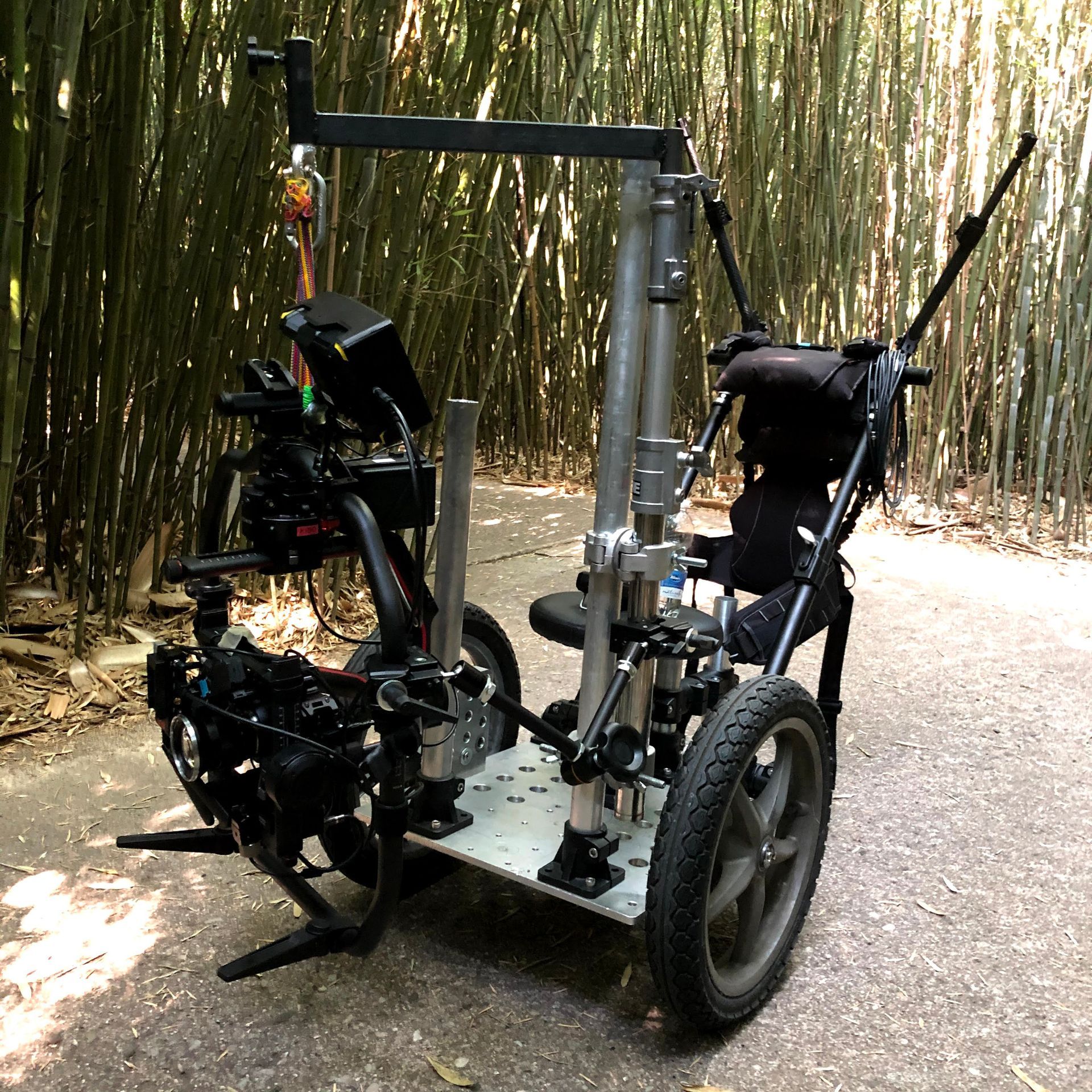 Camera rig on a wheeled platform, outdoors on a path, with a bamboo forest in background.