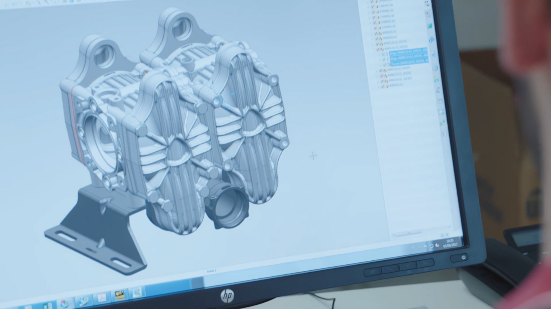 A person looking at a 3D rendering of an engine component on a computer screen.
