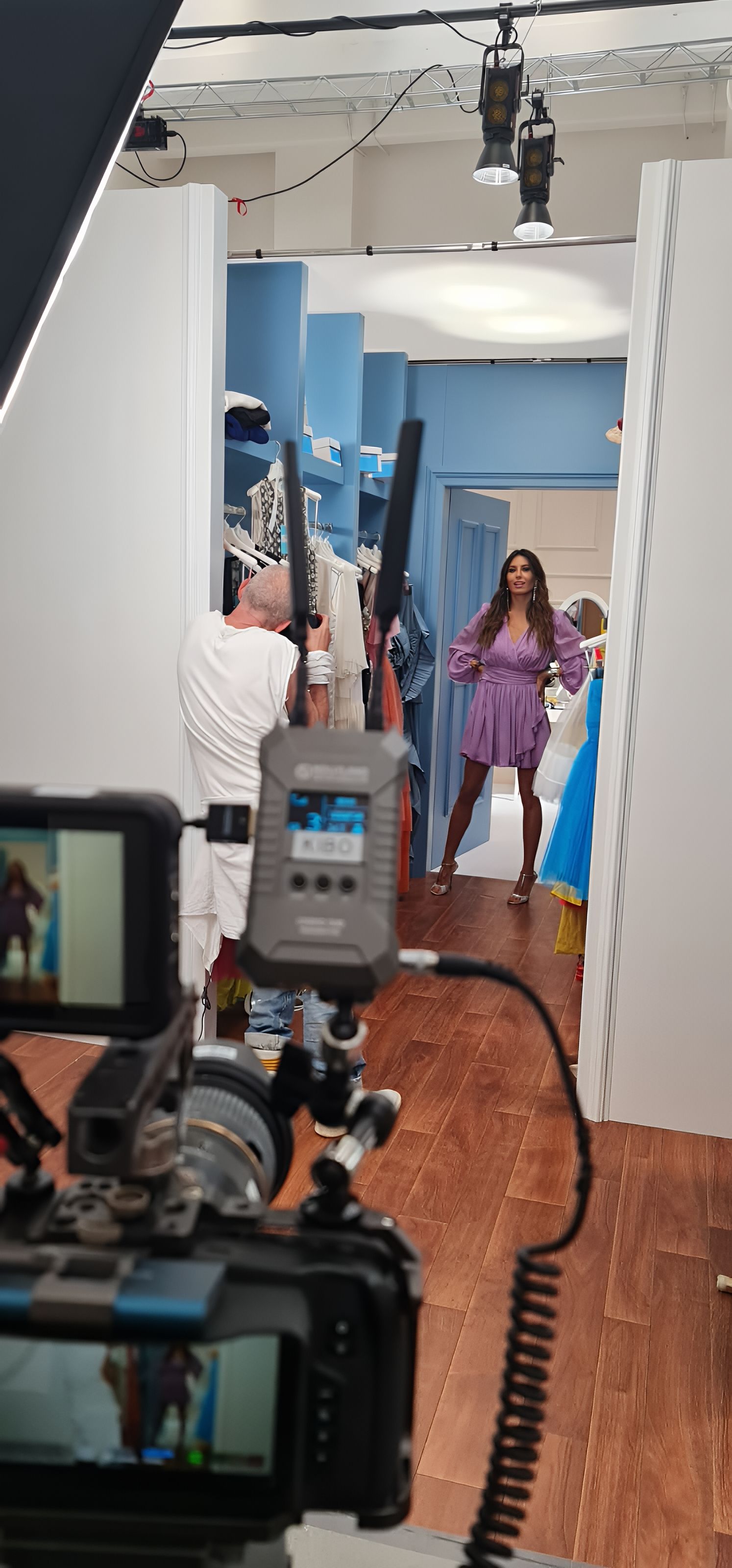 A woman poses during a photo shoot. A camera and equipment are in the foreground.