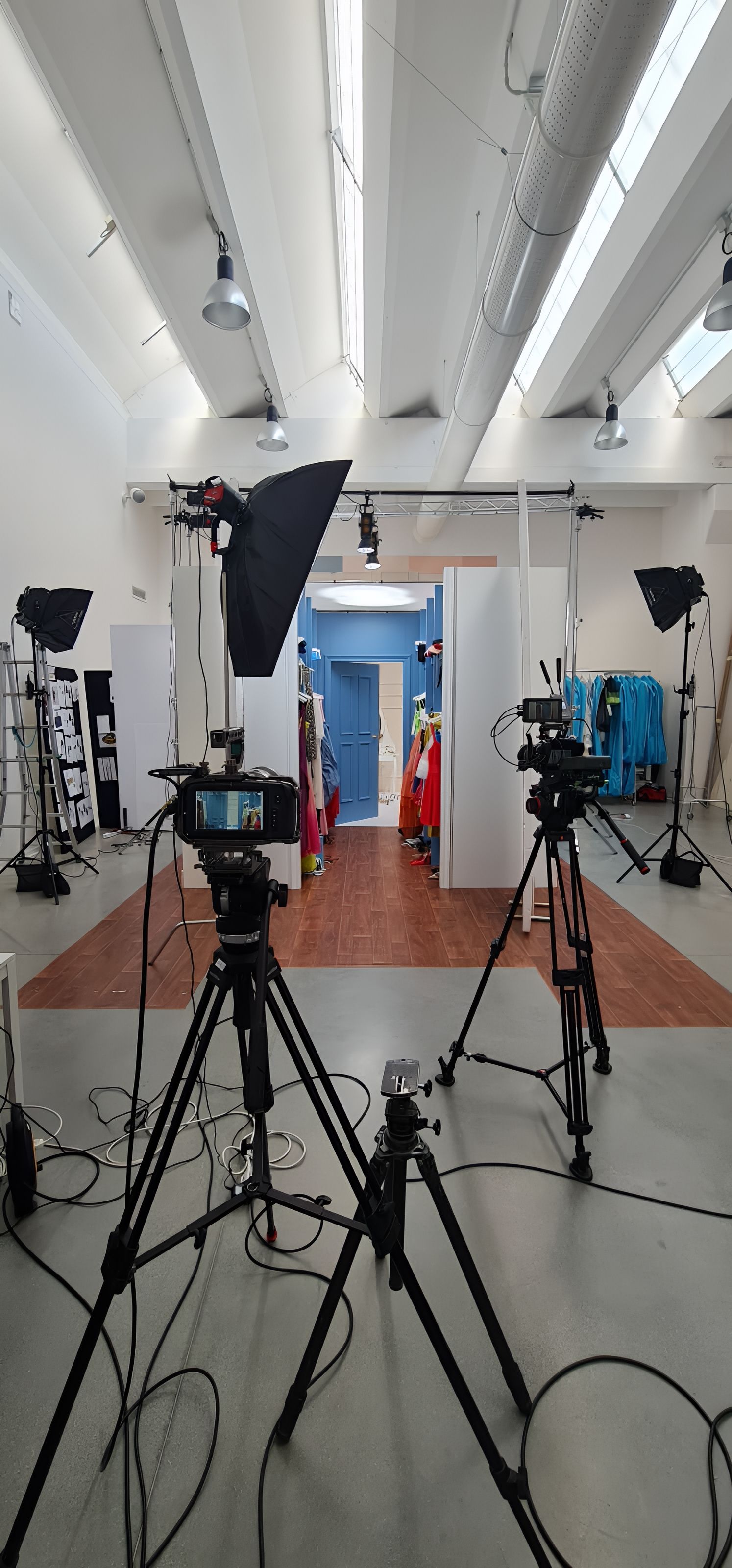 A photo studio setup with cameras on tripods and lighting equipment. Interior shot.