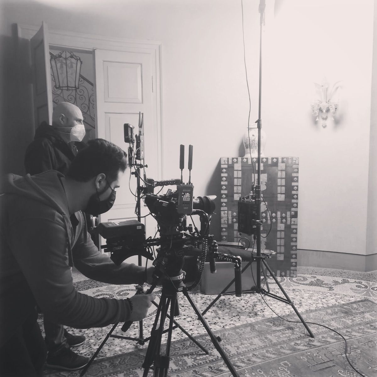 Filmmakers with masks filming indoors with camera and equipment.