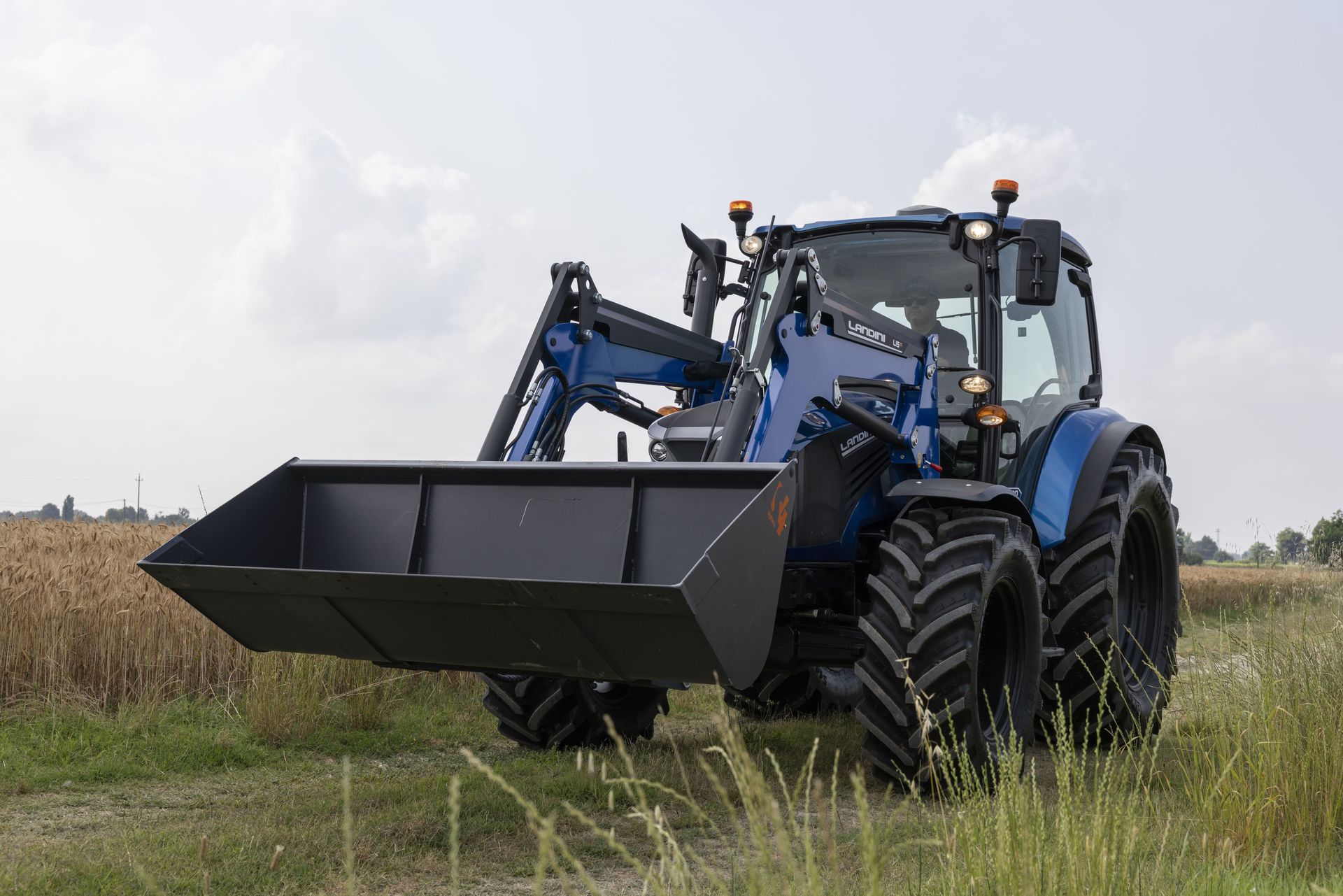 Blue tractor with front loader in a field.