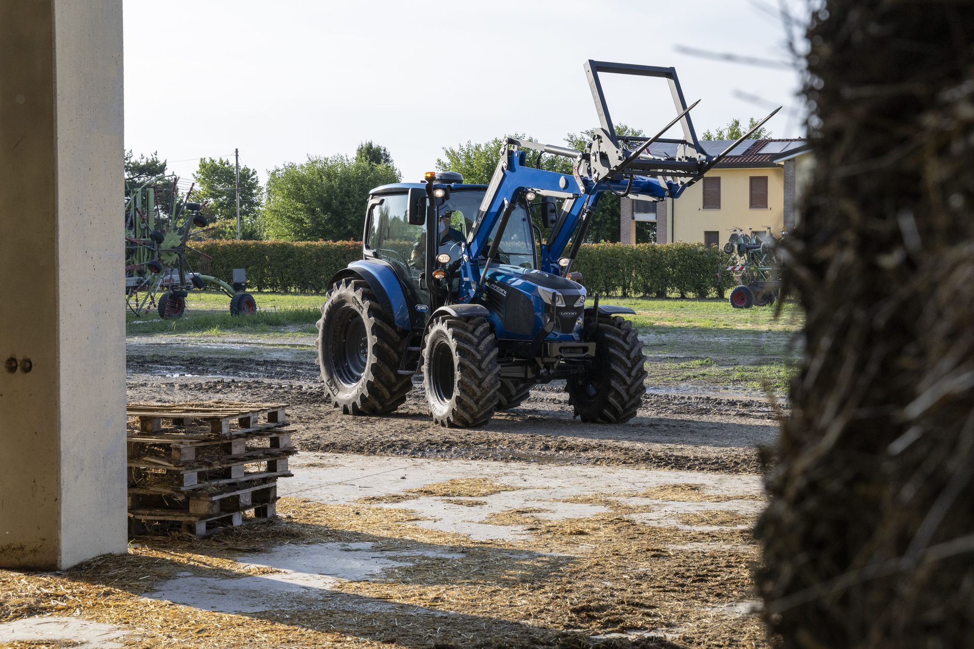 Blue tractor with a front-end loader on a farm.