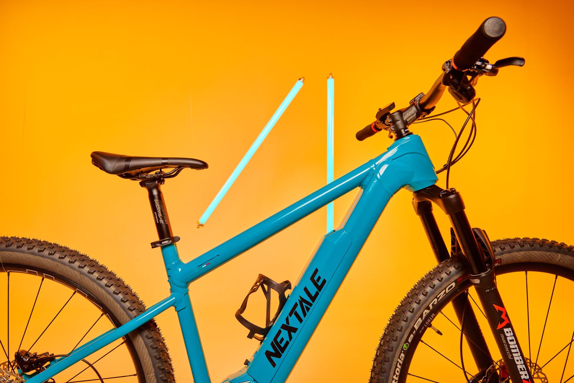 Teal electric mountain bike with neon light trails against a yellow background.