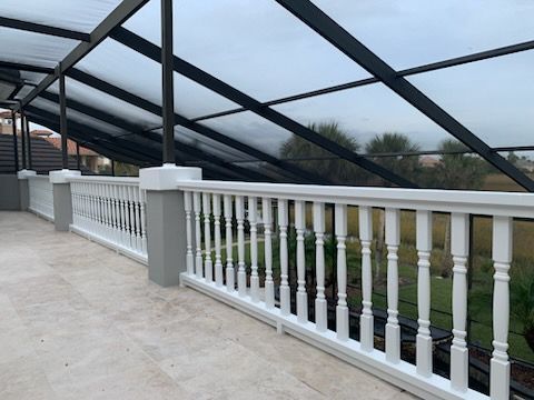 Blue house with porch, surrounded by trees and lawn, under a clear sky.