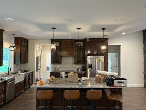 Kitchen with dark brown cabinets, a central island with seating, and pendant lights.