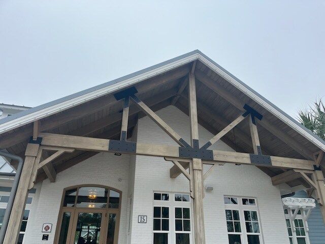 Whitewashed building with wooden beams and dark metal brackets under a gray sky.