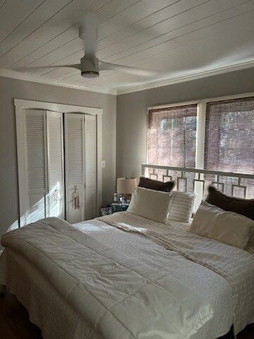 Bedroom with a white bed, closet, windows with shades, and a ceiling fan.