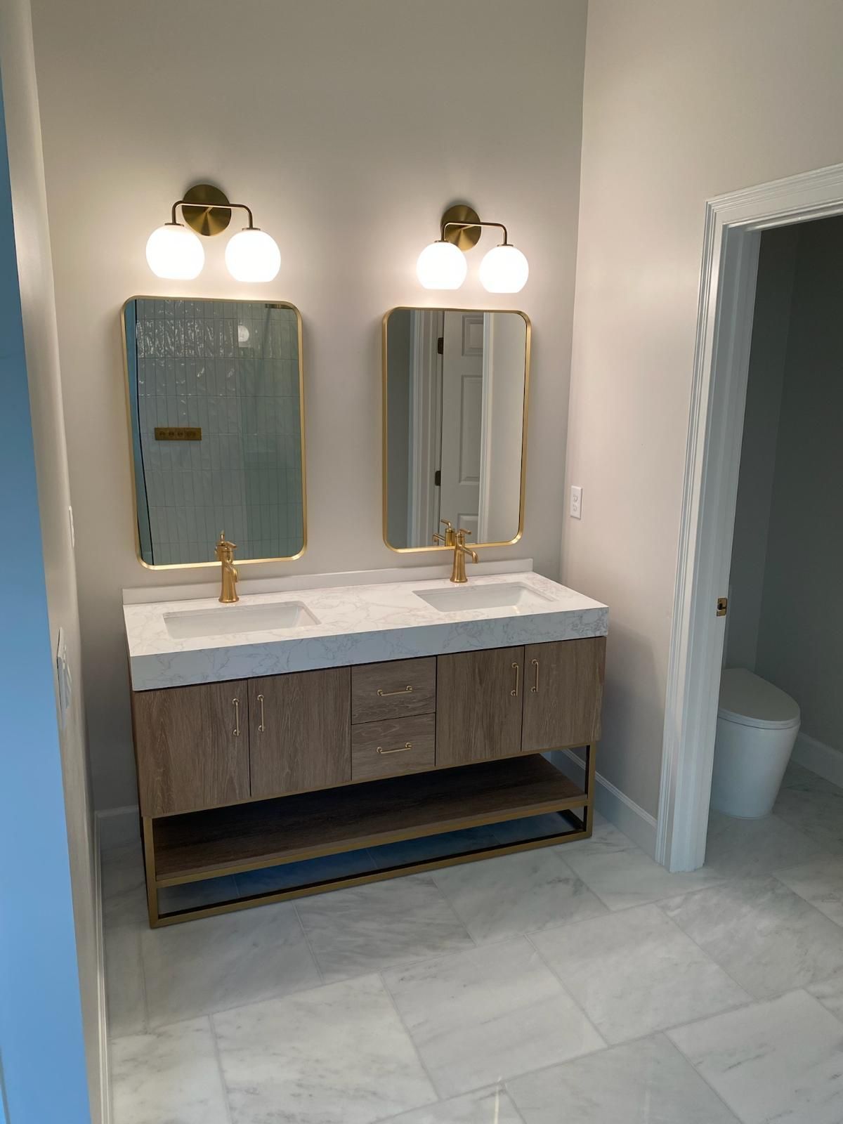 A bathroom with two sinks , two mirrors and a toilet.