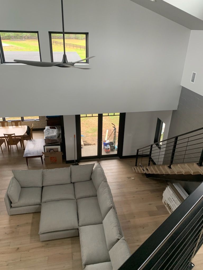 An aerial view of a living room with a sectional couch and stairs.