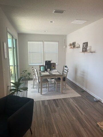 Dining room with table, chairs, and rug, with a dark chair in the corner and shelving on the wall.
