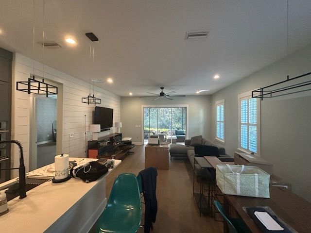 Open-concept living space with kitchen and living room; light walls, dark furniture, and a view to the outdoors.