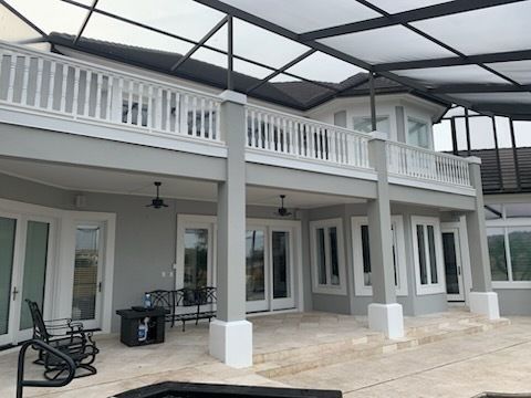 Two-story house with light gray exterior, white trim, and a screened-in patio.