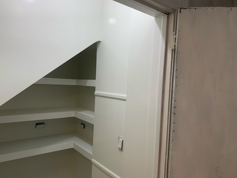 White pantry with shelves. The door is slightly ajar.