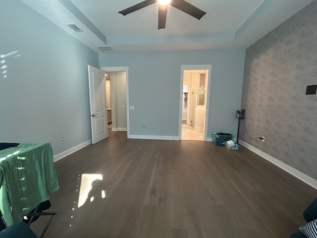Empty bedroom with light blue walls, wood floor, two doorways, and ceiling fan.