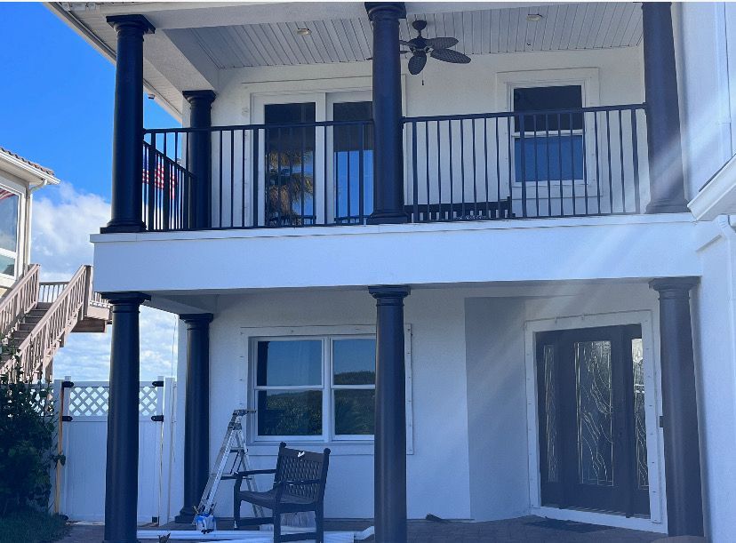 Blue house with porch, surrounded by trees and lawn, under a clear sky.