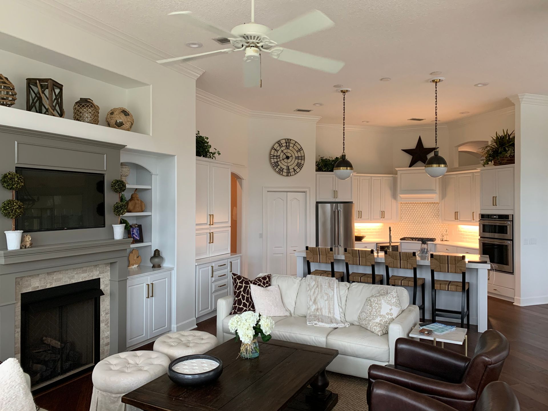A living room with a couch , chairs , a fireplace and a ceiling fan.