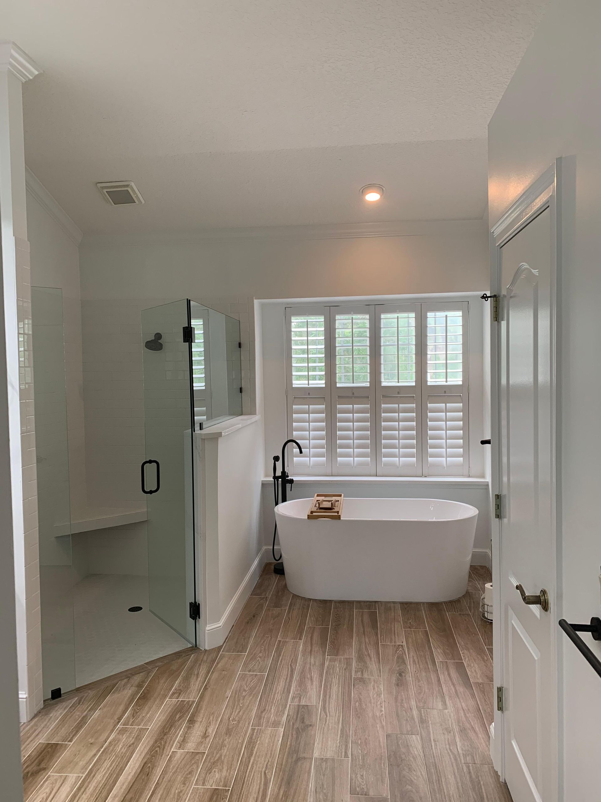 A bathroom with a tub , shower , and window.