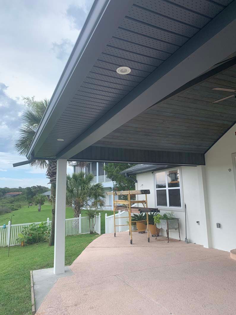 The roof of a house with a covered porch and a ceiling fan.