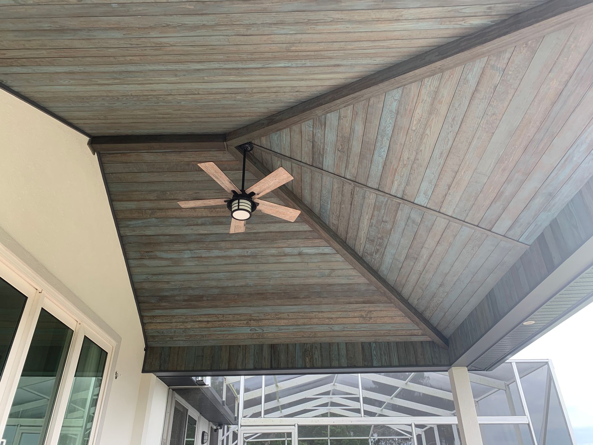 A ceiling fan is hanging from the ceiling of a porch.