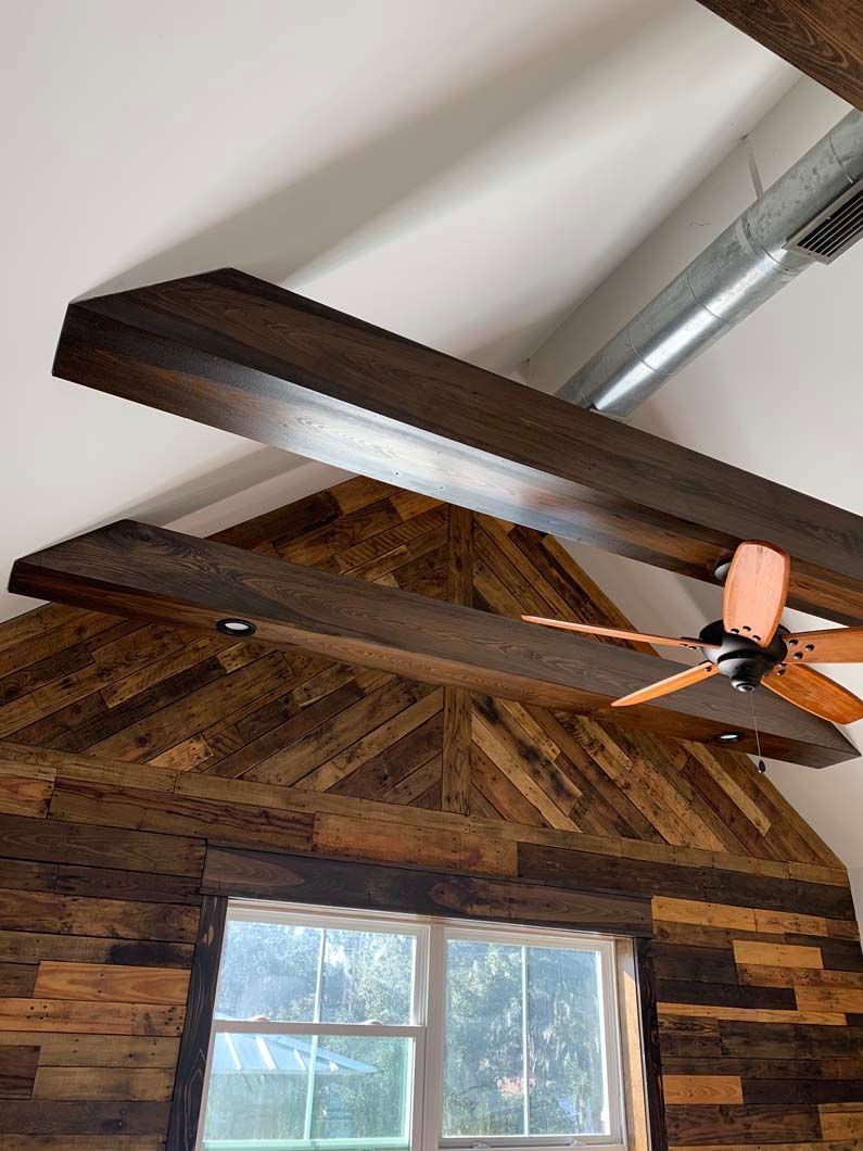 A ceiling fan is hanging from the ceiling of a room with wooden beams.