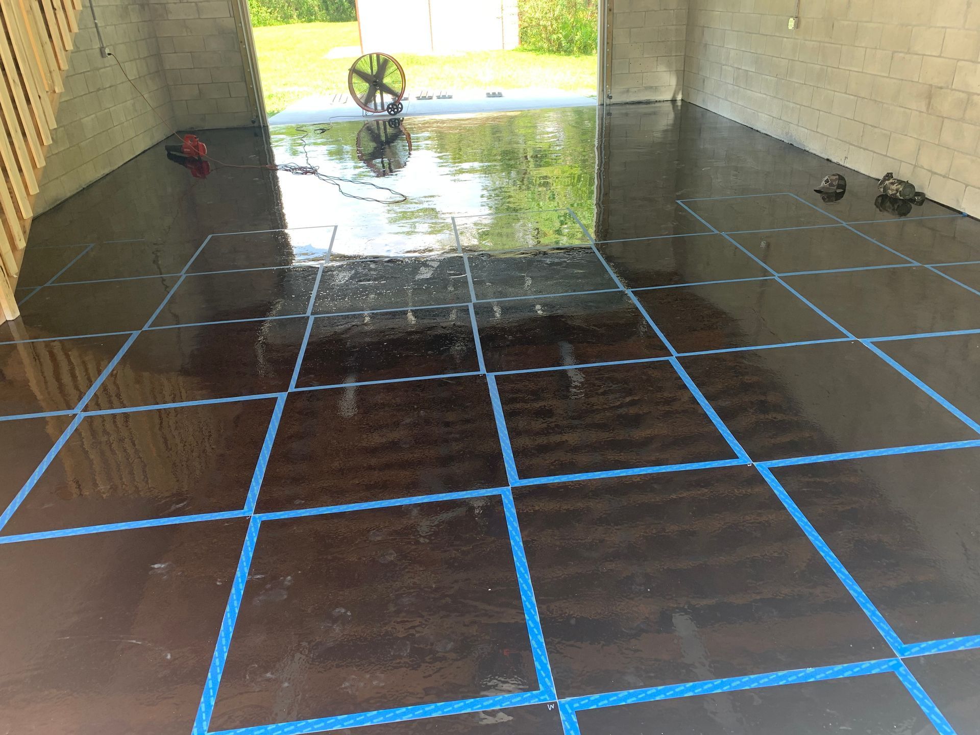 A black tiled floor with blue lines in a garage.