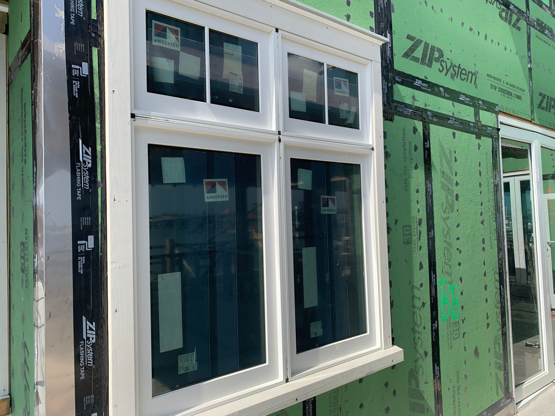 A white window is sitting on a green wall.