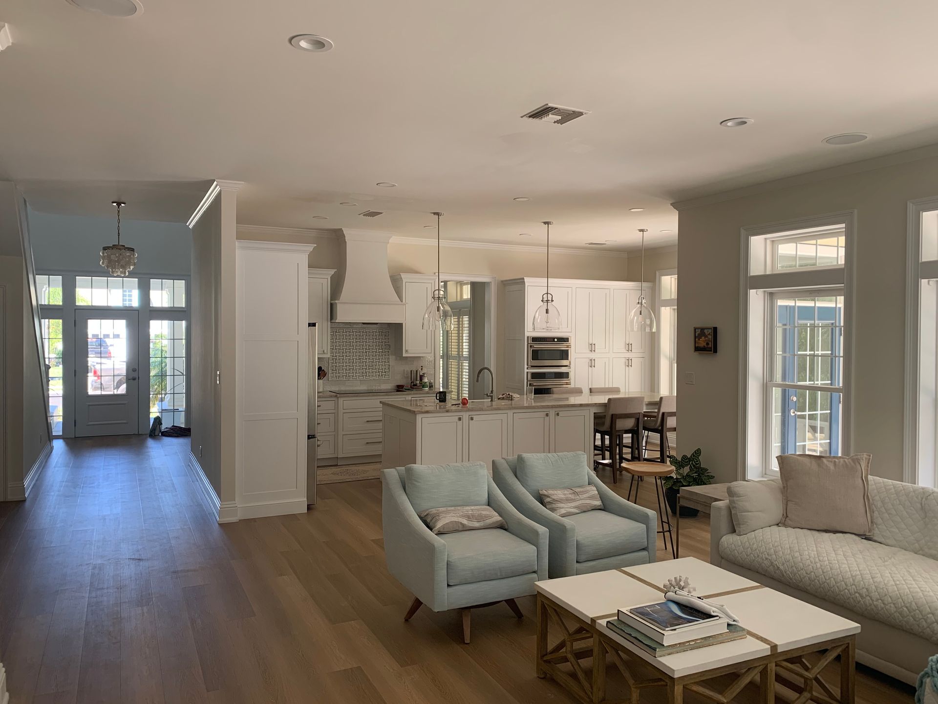 A living room with a couch , chairs , a coffee table and a kitchen.