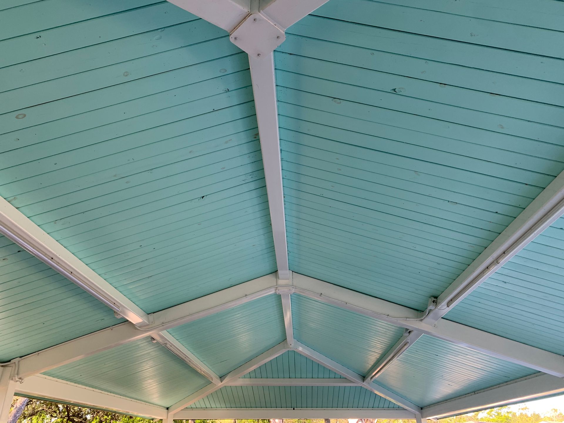 The ceiling of a gazebo is painted blue and white
