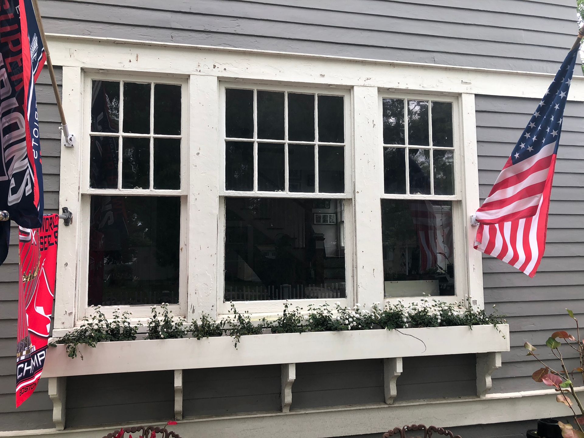 Window with three panes, white trim, and an American flag. A flower box is under the window.