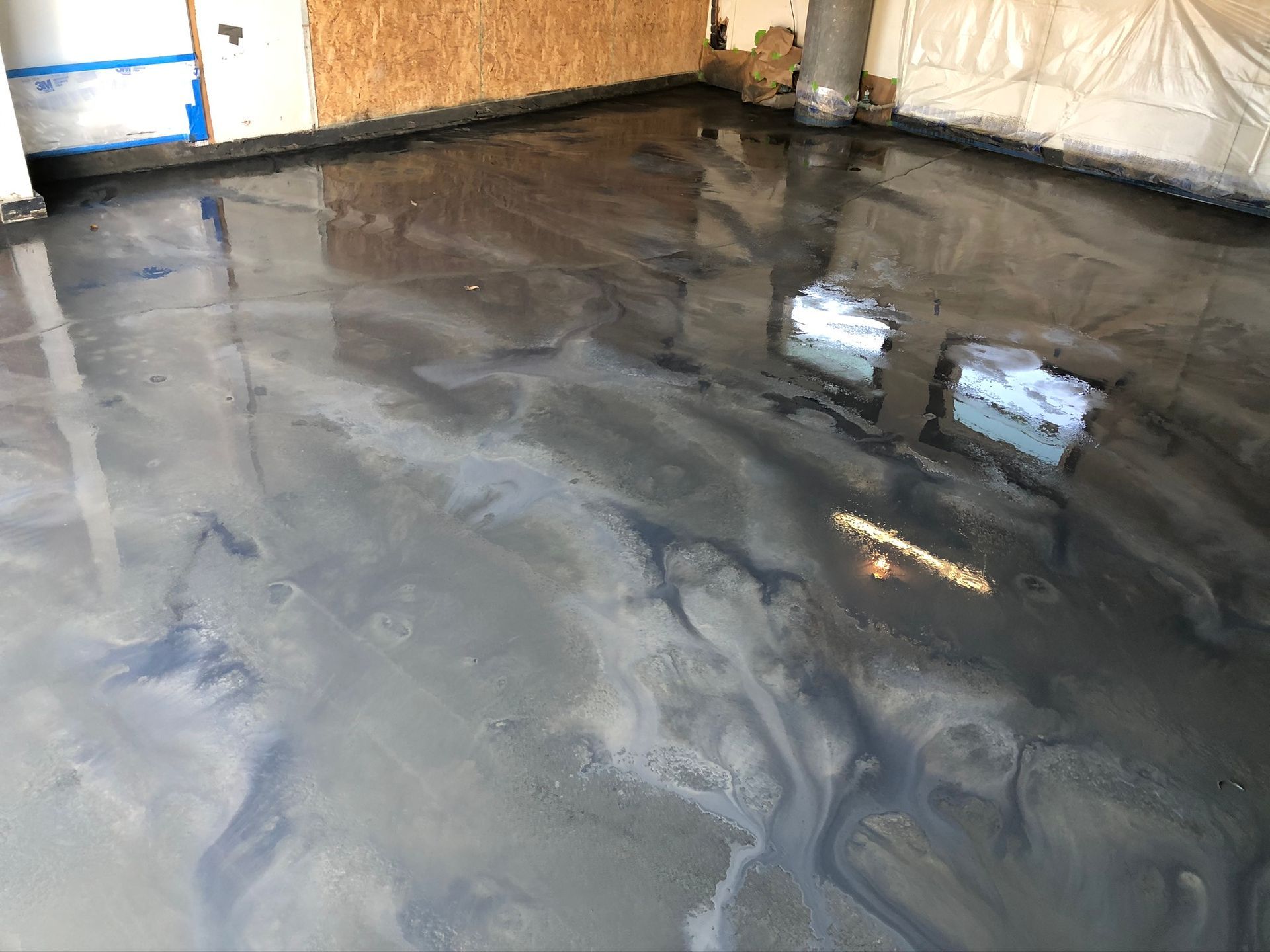 Metallic epoxy floor with swirled gray and black tones, reflecting light.