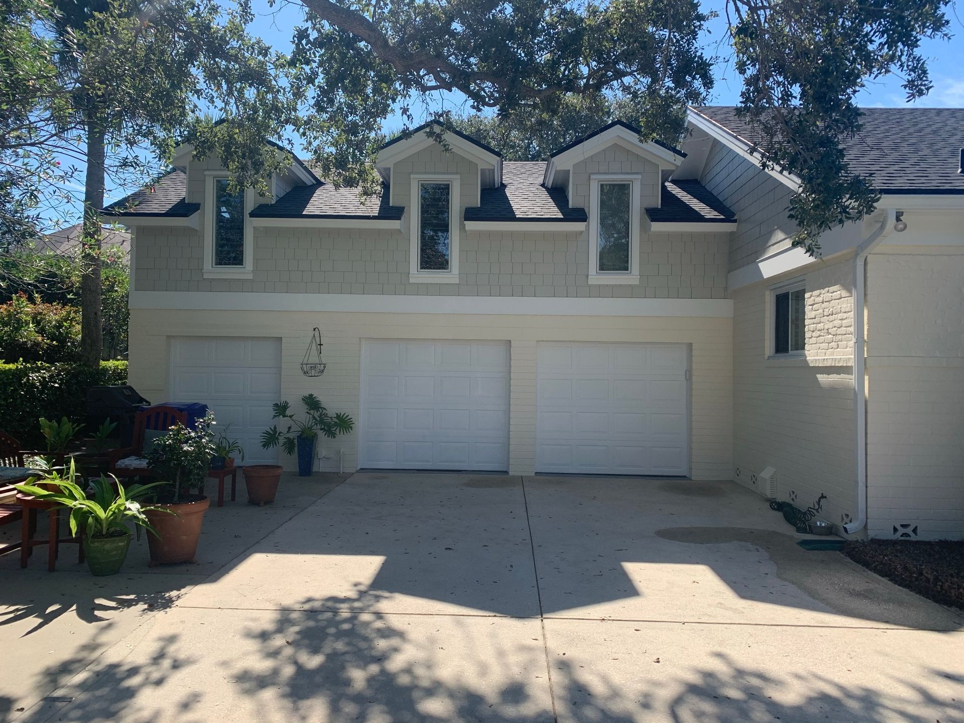 A white house with three garage doors and a driveway