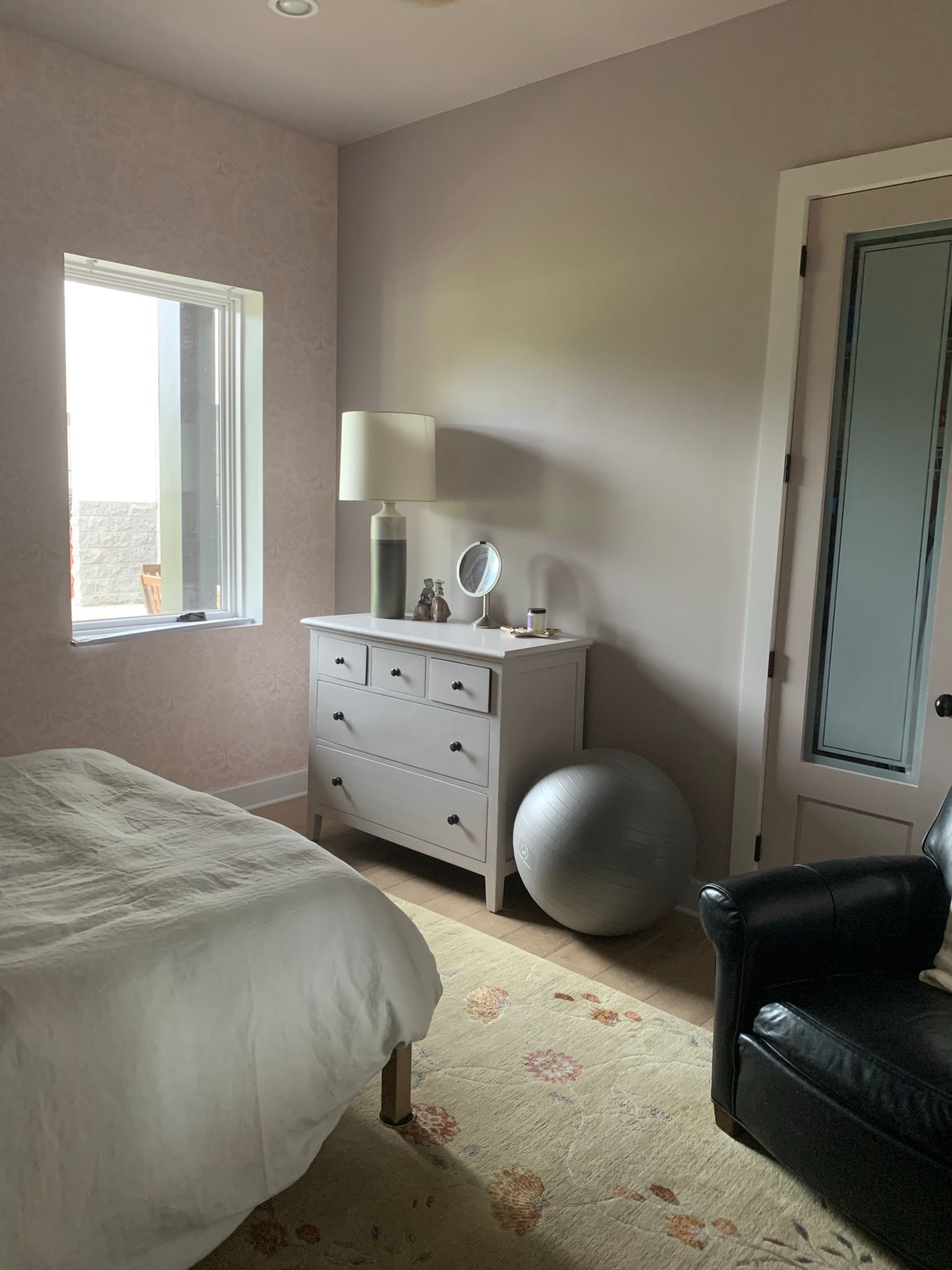 A bedroom with a bed , dresser , chair and window.