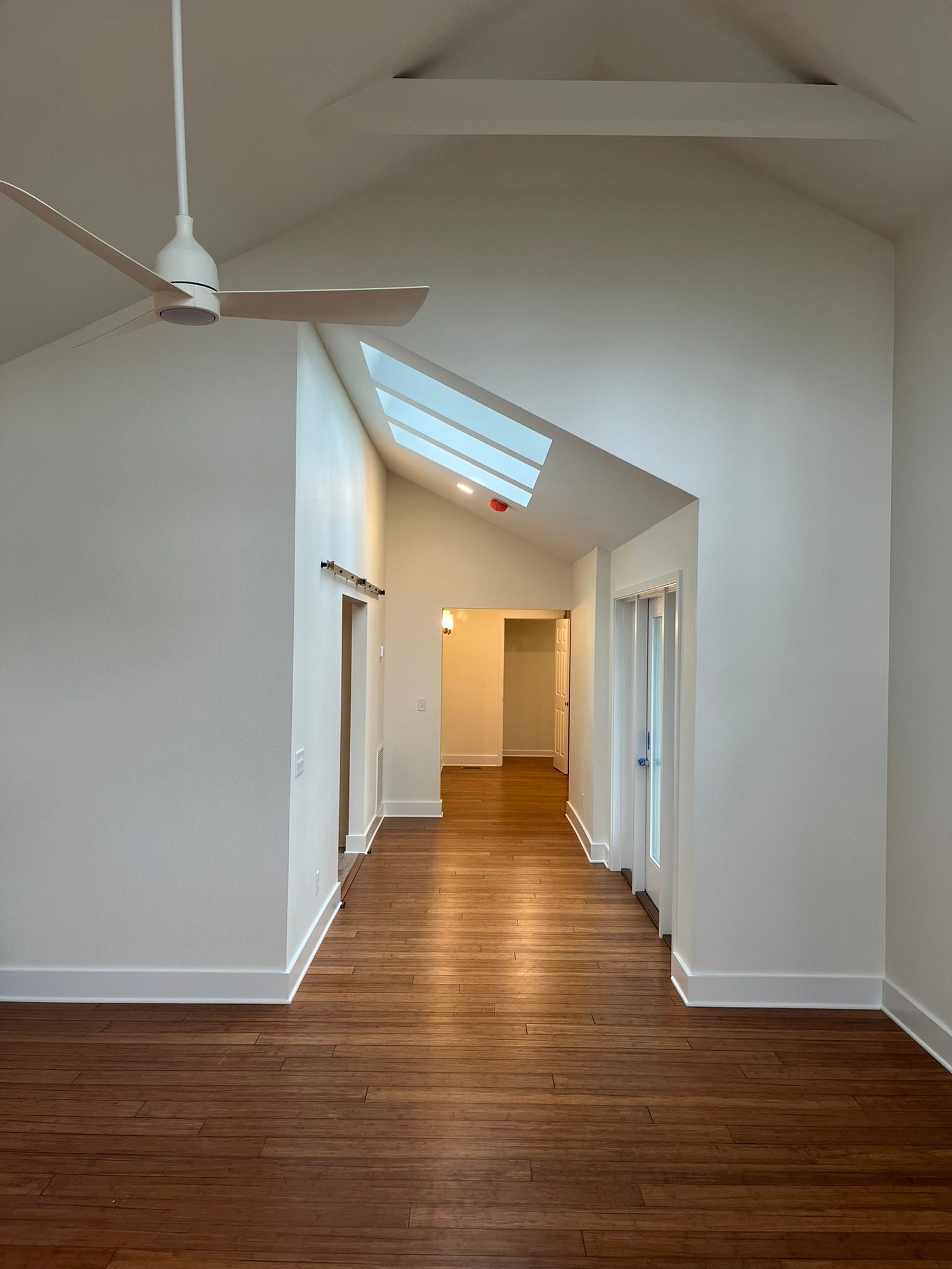 An empty hallway with hardwood floors and a ceiling fan