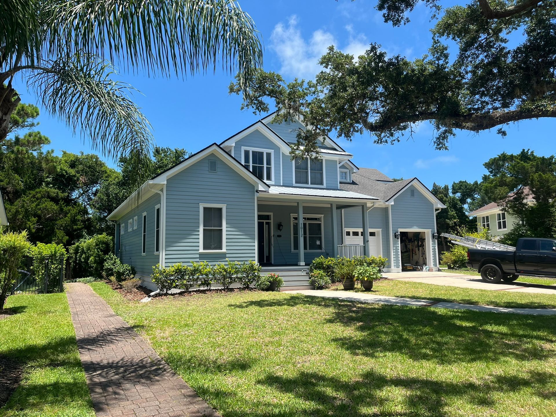 A blue house with a truck parked in front of it on a sunny day.