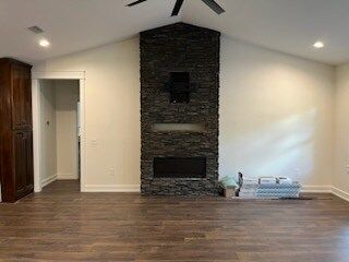 Living room with stone fireplace and wood floors.