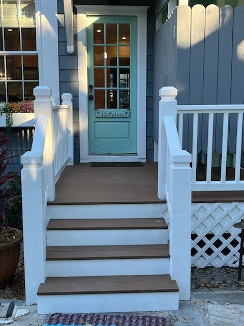 Exterior shot of a teal door with white trim, leading to a small porch with stairs.