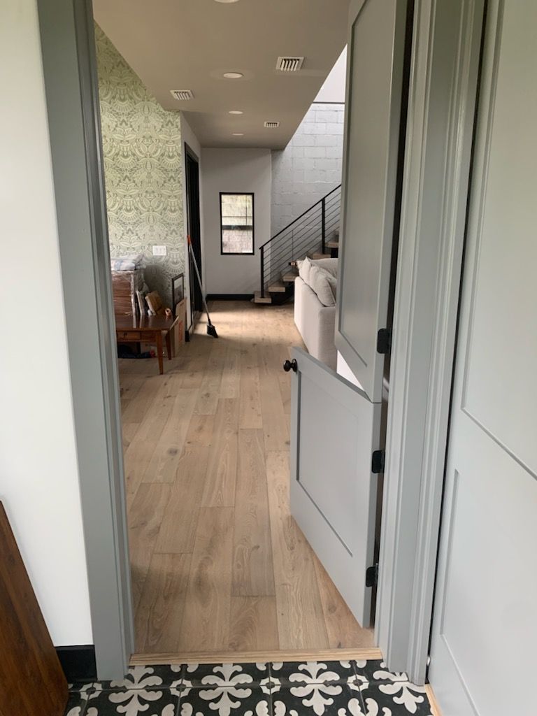 A hallway with hardwood floors and a staircase in the background.