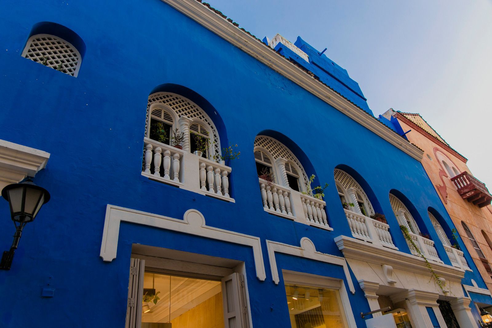 Bright blue building with arched white-trimmed windows and balconies in Cartagena, Colombia.