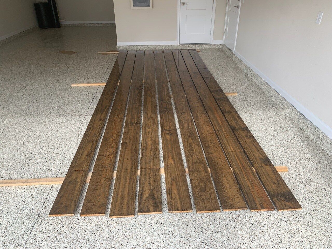A row of wooden boards are sitting on a concrete floor in a garage.