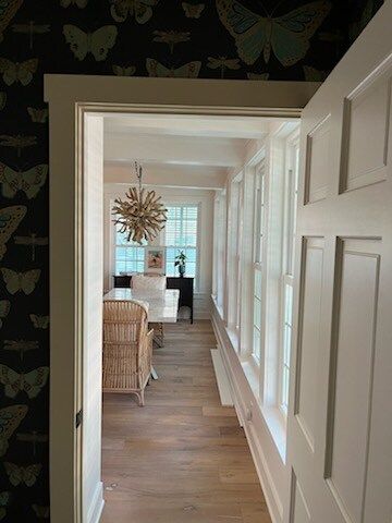 Hallway with wood floors, many windows, and a dining room visible through a doorway; butterfly wallpaper.